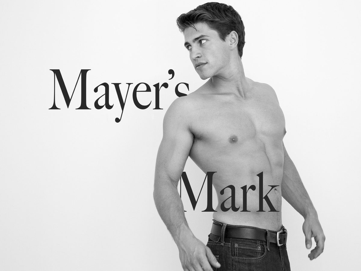 Spread 1 of 8 from Mayers Mark: a bare-chested young man stands against a plain wall in jeans, hand near his belt, looking aside; black and white.