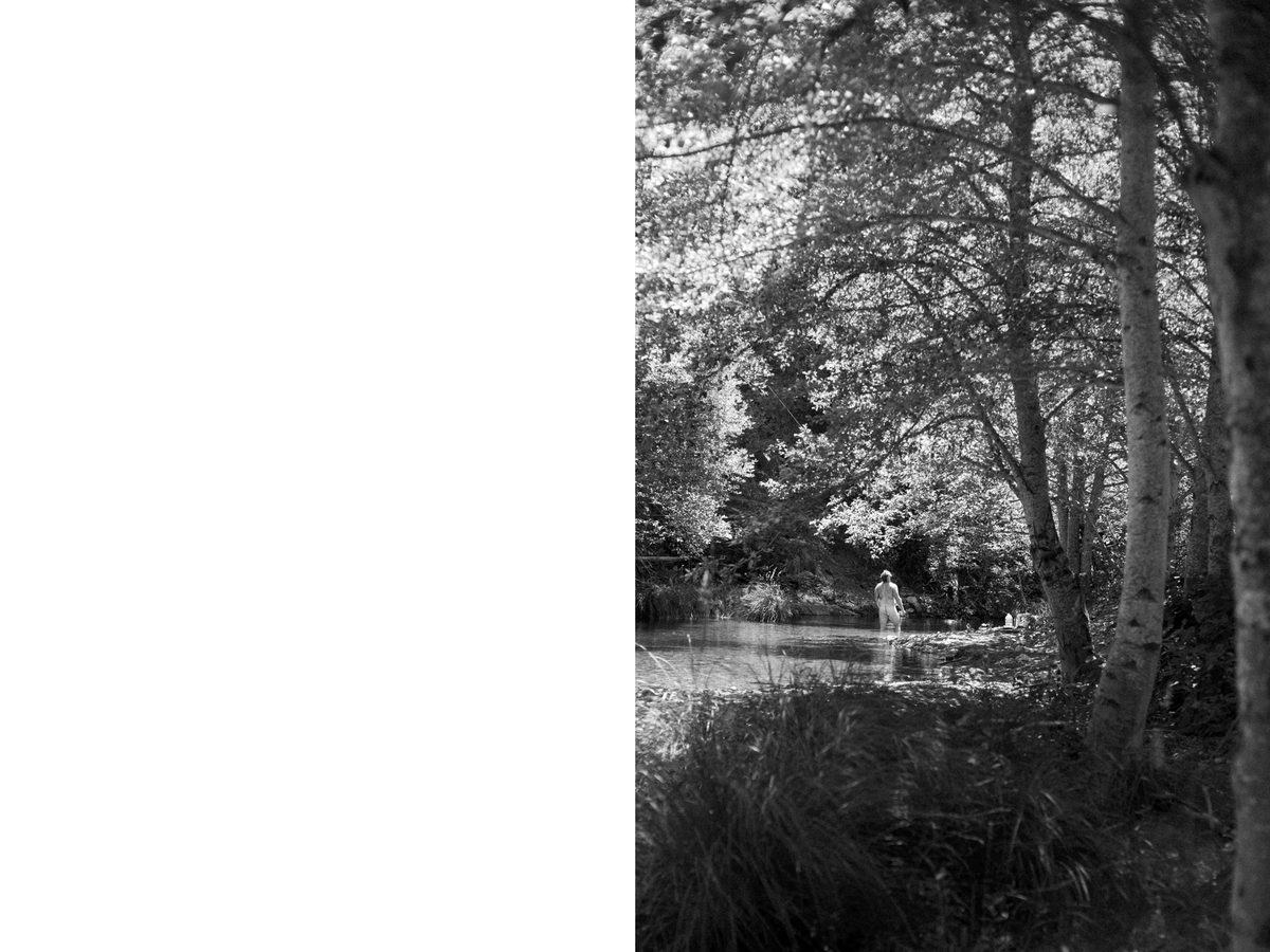 Spread 1 of 7 from Natures Cure: a nude man stands in a wooded stream in the distance, surrounded by birch trees; black and white.